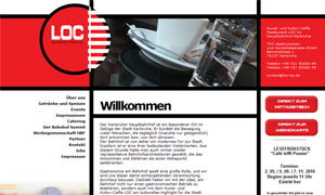 Laptop auf Holztisch mit Kaffeetasse und Glas Wasser, modernes Büro mit rotem und weißem Design