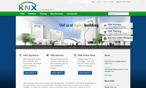 Moderne weiße Gebäudefassade mit KNX-Logo und Bäumen im Vordergrund