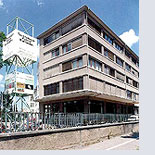 Modernes Bürogebäude aus Beton und Glas mit grauer Fassade unter blauem Himmel